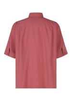 Back view of the PL RAMIE SHIRT by HOMME PLISSÉ ISSEY MIYAKE, a muted red short-sleeved button-up linen blend with a loose fit, collar, visible seams, and buttoned cuffs for breathability.