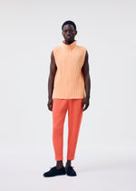 A man with short hair and black shoes stands against a plain background, wearing HOMME PLISSÉ ISSEY MIYAKE's MONTHLY COLORS : APRIL—a sleeveless light orange pleated top and orange pleated pants designed for comfort.