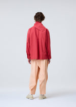 A person faces away, dressed in a loose red long-sleeve top, cream shoes, and peach PLEATS BOTTOMS 1 by HOMME PLISSÉ ISSEY MIYAKE, against a plain light gray background.