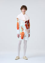 A person with curly hair models the PALETTE dress by HOMME PLISSÉ ISSEY MIYAKE—white, with abstract orange and red patterns—paired with white tights, beige shoes, and a pale pink scarf against a plain light background.
