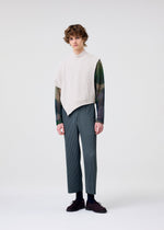 A person stands against a plain white background, wearing the HOMME PLISSÉ ISSEY MIYAKE WAFER KNIT over a sheer long-sleeve shirt and gray pinstriped pants with dark shoes, showcasing a modern layered look while gazing neutrally at the camera.