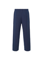 The INLAID KNIT pants by HOMME PLISSÉ ISSEY MIYAKE are navy blue with a lightweight, structured design, elastic waistband, straight-leg cut, and subtle vertical seam details, shown against a white background.