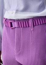 Close-up of a person wearing the HOMME PLISSÉ ISSEY MIYAKE PLEATS BELT in lavender, paired with pleated pants and a tucked-in white shirt.