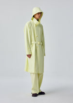 A person stands against a plain white background wearing the OPACITY light yellow hooded coat with detachable hood and matching wide-leg pants, both crafted from a nylon linen blend by HOMME PLISSÉ ISSEY MIYAKE, paired with dark shoes.