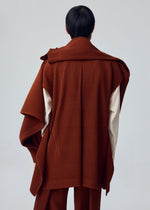 A person stands with their back to the camera, wearing the MOTION BLUR brown pleated jersey jacket with cape-like detail over cream sleeves by HOMME PLISSÉ ISSEY MIYAKE, set against a plain light background.