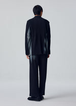 A person faces away wearing the IN THE SHADOW black pinstripe suit by HOMME PLISSÉ ISSEY MIYAKE, with matching pants and black shoes against a plain light background.