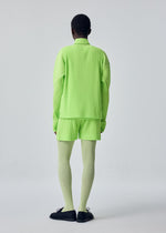 A person is seen from behind against a plain background, wearing the HOMME PLISSÉ ISSEY MIYAKE COLOR PLEATS 1: a bright neon green long-sleeve top paired with vibrant, sporty pleated shorts in quick-drying polyester, complemented by light green tights and black shoes.