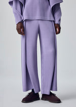 A person wears the HOMME PLISSÉ ISSEY MIYAKE MOTION BLUR set—lavender rib-knit pleated jersey pants and a long-sleeve top—with dark brown shoes. The image is shoulder-cropped against a plain background.