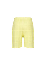 HOMME PLISSÉ ISSEY MIYAKE’s LACE GRID PLEATS shorts in yellow feature a textured, knee-length silhouette with an elastic waistband and drawcord waist, styled against a plain white background. Crafted from a soft cotton-blend polyester fabric, these shorts showcase a subtle grid pattern for elevated visual interest.