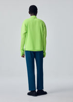A person stands facing away, wearing the HOMME PLISSÉ ISSEY MIYAKE COLOR PLEATS 1 blue pleated pants paired with a bright green ribbed long-sleeve sporty top and black shoes, set against a plain light gray background.