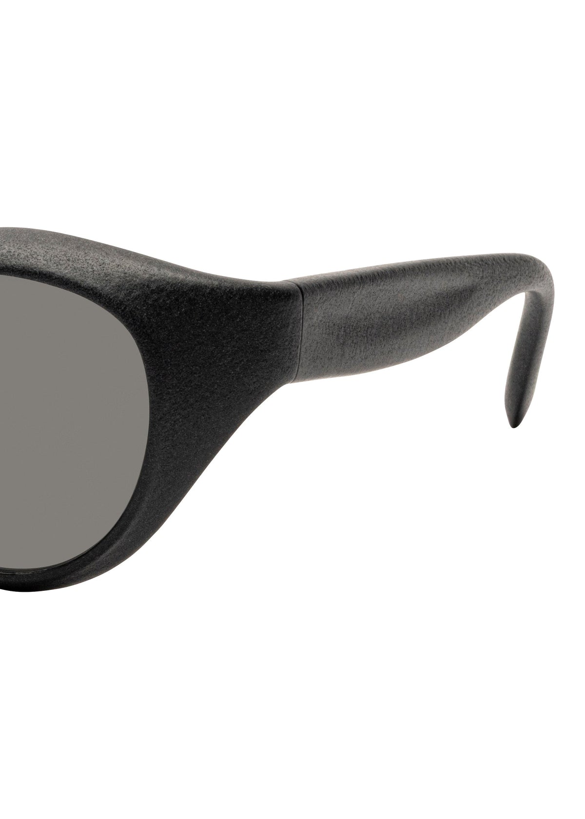 Close-up of the right side of ISSEY MIYAKE EYES GRIT-BOSTON black Boston-style sunglasses, featuring a thick frame, gray lens, and curved temple arm against a white background. view 4 of 6