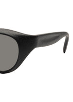 Close-up of the right side of ISSEY MIYAKE EYES GRIT-BOSTON black Boston-style sunglasses, featuring a thick frame, gray lens, and curved temple arm against a white background.