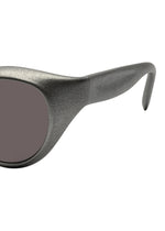Close-up of the left side of ISSEY MIYAKE EYES GRIT-BOSTON sunglasses, featuring a thick, textured dark gray frame and dark tinted lens, set against a white background.