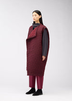 A woman with straight dark hair models the ONE CLOTH PUFF by ISSEY MIYAKE ONLINE STORE: a long maroon jacquard vest worn over a dark gray top and maroon pants. She stands against a plain background, wearing black shoes and gazing off to the side.