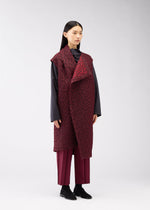 A woman with straight black hair models the ONE CLOTH PUFF by ISSEY MIYAKE ONLINE STORE— a long jacquard weave burgundy vest over a dark gray top and matching burgundy pants, set against a plain light gray background.