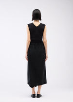 A person with short dark hair, seen from behind, wears a sleeveless black V-back top and SEAMLESS BOTTOMS by 132 5. ISSEY MIYAKE that resemble a long skirt. They stand against a plain white background in black slip-on shoes.
