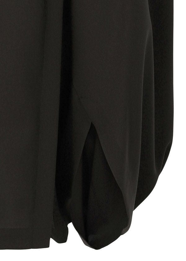 Close-up of the hem on SEAMLESS BOTTOMS by 132 5. ISSEY MIYAKE, showing soft, draped black fabric with a gathered, rounded detail for a relaxed silhouette. view 6 of 11