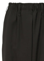 Close-up of SEAMLESS BOTTOMS by 132 5. ISSEY MIYAKE—black skirt with an elastic waistband and belt loops, made from recycled polyester. Its textured fabric and pleats offer a relaxed silhouette inspired by sarouel pants.