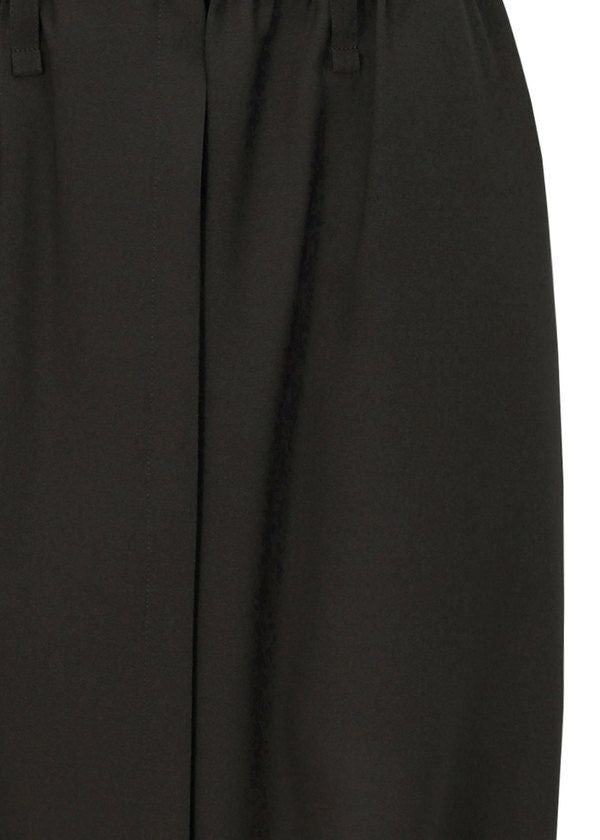 Close-up of SEAMLESS BOTTOMS by 132 5. ISSEY MIYAKE: black sarouel pants with a smooth, slightly shiny recycled polyester fabric, featuring a waistband, belt loops, and central crease. view 6 of 12