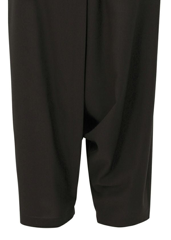 A close-up of the SEAMLESS BOTTOMS by 132 5. ISSEY MIYAKE highlights their black, dropped crotch design, relaxed silhouette, and the fabric detail from thigh to just below the knees. view 8 of 12