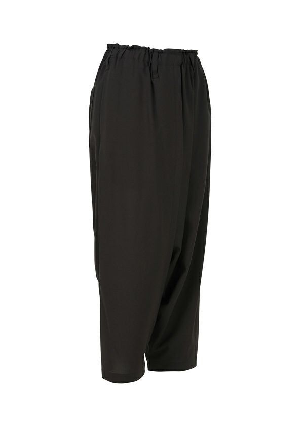 Zoomed view SEAMLESS BOTTOMS by 132 5. ISSEY MIYAKE are black sarouel pants with a relaxed, draped silhouette and elastic waistband, crafted from recycled polyester and shown on a white background.