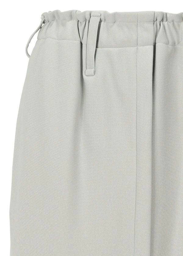 Close-up of the JERSEY BOTTOMS BASIC by 132 5. ISSEY MIYAKE, showcasing light gray polyester fabric, an elastic waistband with drawstring, fabric belt loop, and a vertical front seam with a soft, textured appearance. view 5 of 11