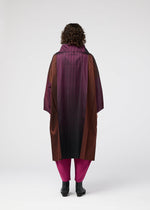 A person with curly hair stands facing away, wearing the GRADATION COAT by 132 5. ISSEY MIYAKE in purple, burgundy, and black with a large collar, paired with magenta pants and black shoes, against a plain white background.
