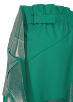 Close-up of NO.17 FOIL by 132 5. ISSEY MIYAKE: a green fabric garment with metallic silver sheer overlay, matching green belt with silver buckle, and an innovative folding structure that creates textured, layered, and draped details.