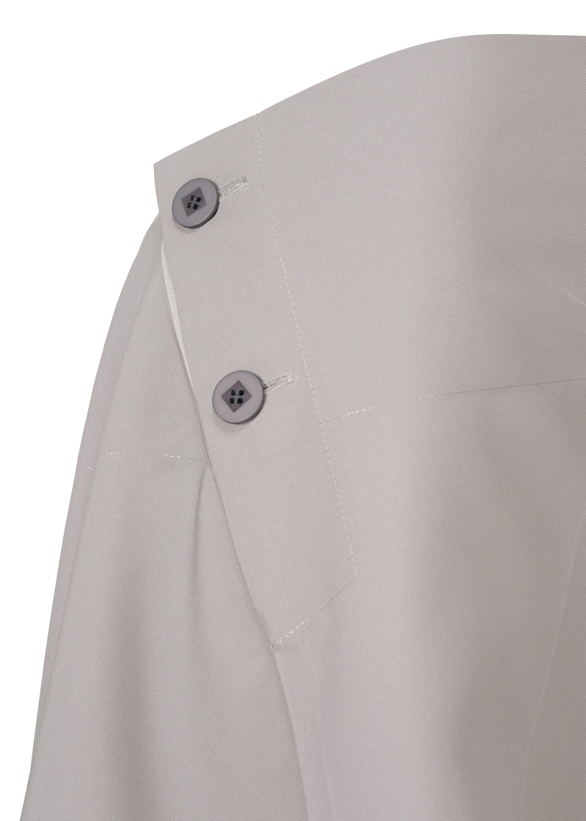 Zoomed view Close-up of the NO.17 PRINT skirt by 132 5. ISSEY MIYAKE in light gray, featuring a seam detail and two gray buttons at the fabric edge, with visible stitching and garment texture.