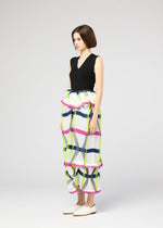 A woman with a short bob wears the NO.6 TRANSLUCENT skirt by 132 5. ISSEY MIYAKE—a high-waisted, colorful plaid piece with ruffles, pleats, and unique folds—paired with a sleeveless black top and white slip-on shoes, standing sideways.