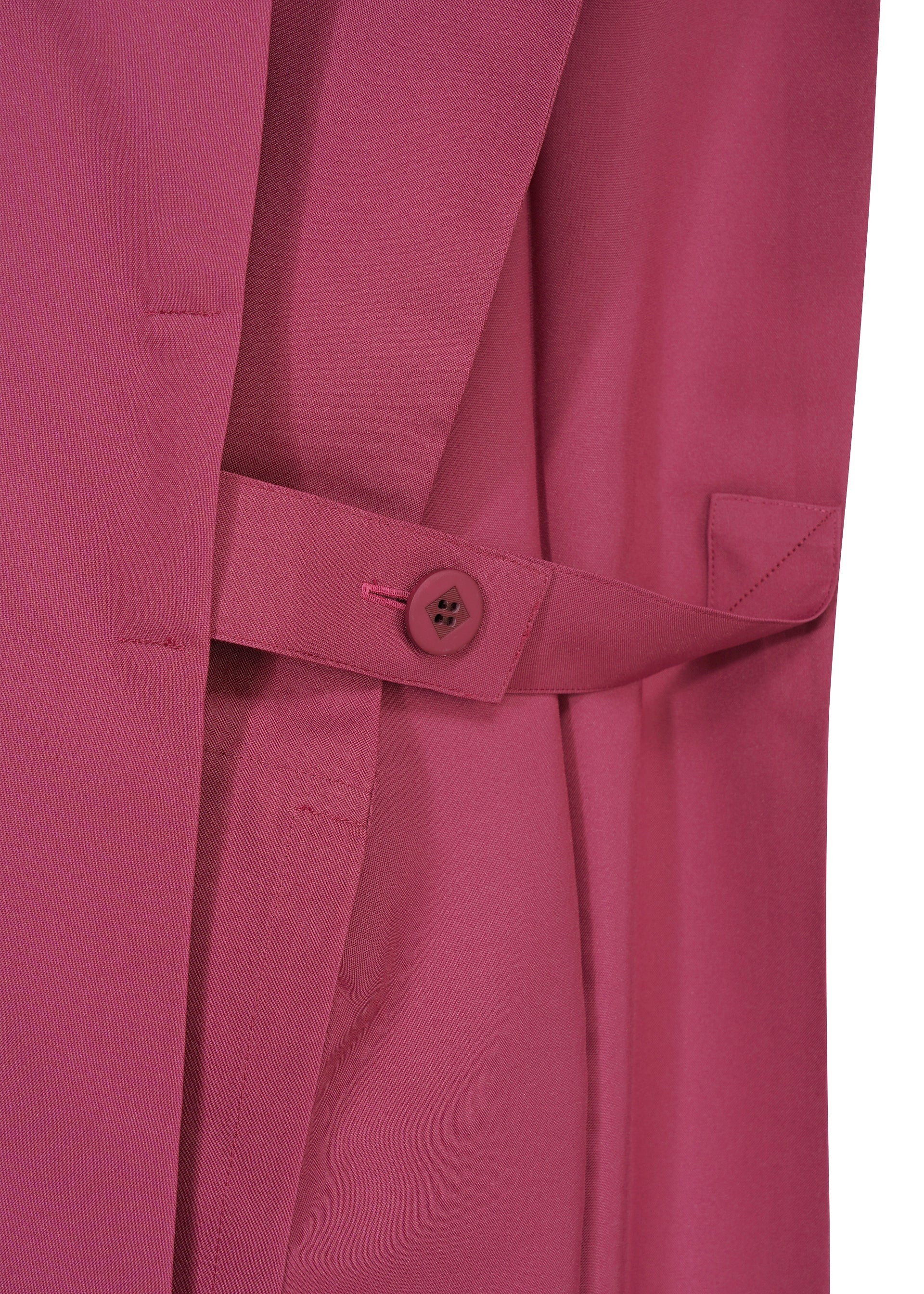 Zoomed view Close-up of a magenta 132 5. FLAT 1 coat by 132 5. ISSEY MIYAKE, featuring a buttoned belt strap, welt pocket, and exquisite garment structure.