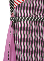 Close-up of the FACET dress by 132 5. ISSEY MIYAKE, showcasing a Nassen print with black, white, and pink diagonal stripes, a thin striped waist belt, solid pink panel on the left, and bold red and white stripe accents at the top.