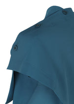 Close-up of the shoulder area of a teal FACET SOLID garment by 132 5. ISSEY MIYAKE, featuring a cape-like overlay and three dark buttons on the shoulder seam, made from plant-derived polyester plain fabric, set against a white background.