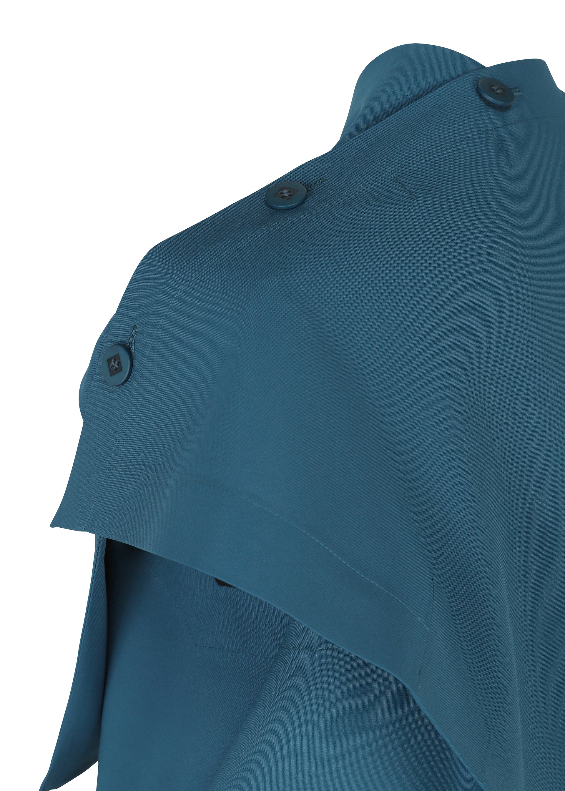 Zoomed view Close-up of the shoulder area of a teal FACET SOLID garment by 132 5. ISSEY MIYAKE, featuring a cape-like overlay and three dark buttons on the shoulder seam, made from plant-derived polyester plain fabric, set against a white background.