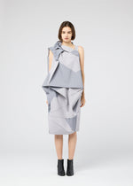 A woman faces forward in a geometric light grey NO.17 PRINT dress by 132 5. ISSEY MIYAKE, featuring angular folds and layers, paired with black ankle boots against a plain white background.