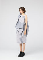 A woman stands in profile against a white background, wearing the NO.17 PRINT dress by 132 5. ISSEY MIYAKE—featuring sculptural, layered folds in light gray—and black ankle boots.