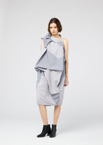 A woman stands against a plain background wearing the NO.17 PRINT dress by 132 5. ISSEY MIYAKE, featuring geometric folds and draping in light gray, paired with black ankle boots. She faces the camera neutrally, arms relaxed at her sides.