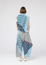 A person with short brown hair stands facing away, wearing the 132 5. ISSEY MIYAKE FACET—a loose, flowing outfit in bold blue, black, and white Nassen print. Its asymmetrical drape and geometric patterns create striking visual effects.