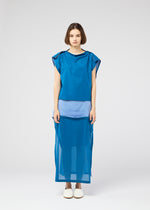 A woman with short brown hair faces forward wearing the SHEER FOLIO loose-fit blue dress by 132 5. ISSEY MIYAKE, featuring fabric layers and sheer panels over a light blue petticoat, paired with white slip-on shoes against a plain white background.