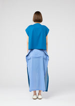 A person with short brown hair faces away, wearing the SHEER FOLIO dress by 132 5. ISSEY MIYAKE—blue top, layered light blue dress with side slits, and white shoes—set against a simple, light background.