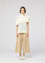 Against a plain light gray background, a person with straight, chin-length brown hair wears the FOLD RAMIE PRINT top by 132 5. ISSEY MIYAKE, paired with wide beige culotte pants and white slip-on shoes.