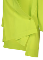 Close-up of the FLAT TUCK T by 132 5. ISSEY MIYAKE in bright lime green, featuring layered smooth lightweight fabric, an asymmetrical hem, and a small button detail.