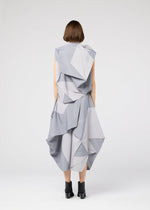 A person with short brown hair, seen from behind, wears the 132 5. ISSEY MIYAKE NO.17 PRINT, a light gray geometric origami-inspired dress with folding structure and black ankle boots against a plain white background.
