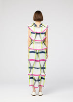 A person with short brown hair faces away in the 132 5. ISSEY MIYAKE NO.6 TRANSLUCENT: a white outfit with bold navy, pink, and yellow grids, ruffled fold-inspired details, sheer accents, and white shoes against a plain light background.