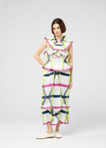 A woman wears the NO.6 TRANSLUCENT outfit by 132 5. ISSEY MIYAKE—loose, sleeveless top and wide-leg pants in a colorful grid print with sheer fabric—styled simply with white slippers against a plain backdrop and a neutral expression.