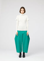 A woman with a bob haircut wears the FLAT RIB KNIT 1 seamless white turtleneck sweater by 132 5. ISSEY MIYAKE and wide teal-green pants, standing against a plain light gray background, facing forward.