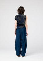 Seen from behind, a person with short curly hair wears the 132 5. ISSEY MIYAKE FACET KNIT sleeveless dark navy top and loose, wide-legged blue pants, standing against a plain light background.