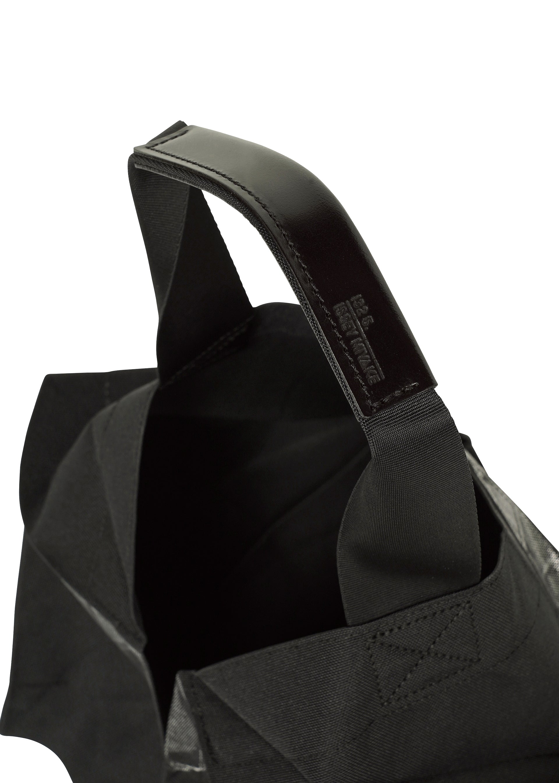 Zoomed view Close-up of the No.1-BG tote by 132 5. ISSEY MIYAKE: black fabric, sturdy leather handles, fine stitching, and a peek inside, all shown against a white background.