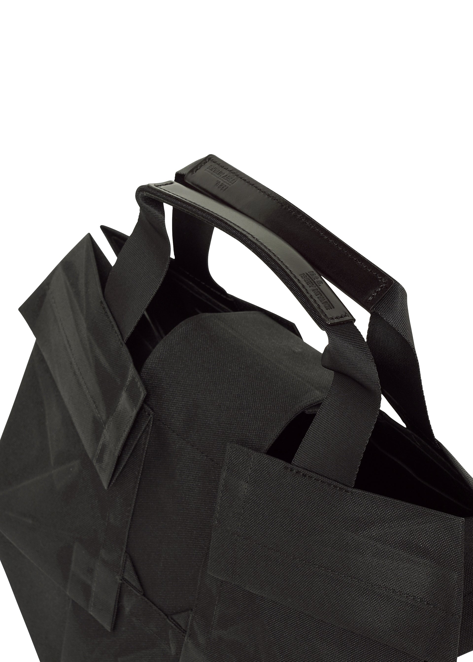 Zoomed view Close-up of the No.6-BG tote bag by 132 5. ISSEY MIYAKE: black fabric, sturdy reinforced handle, folding design, and a simple modern look—all against a white background for practical and stylish everyday use.