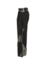 Side view of F-BT pants by 132 5. ISSEY MIYAKE in black recycled polyester, featuring an angular geometric design with shiny metallic silver foil on the waistband and legs, displayed against a white background.
